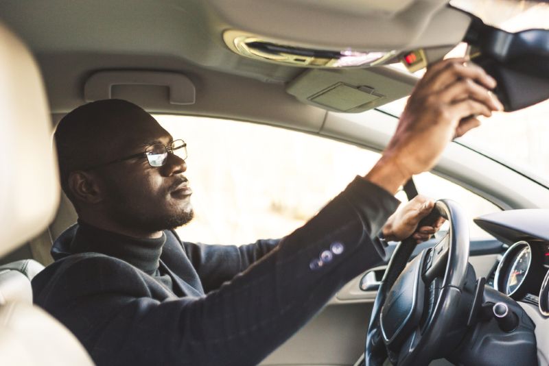 man looking in the center mirror of his car