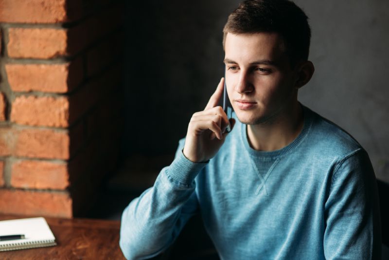 young man on his phone in the corner of his room